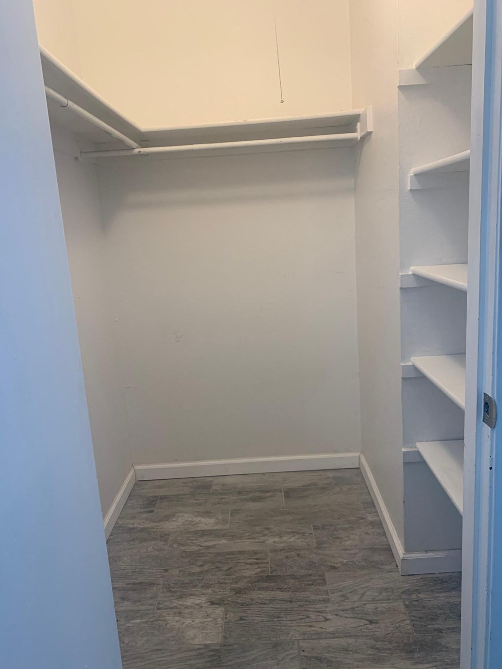 a walk in closet with shelves and a wood floor