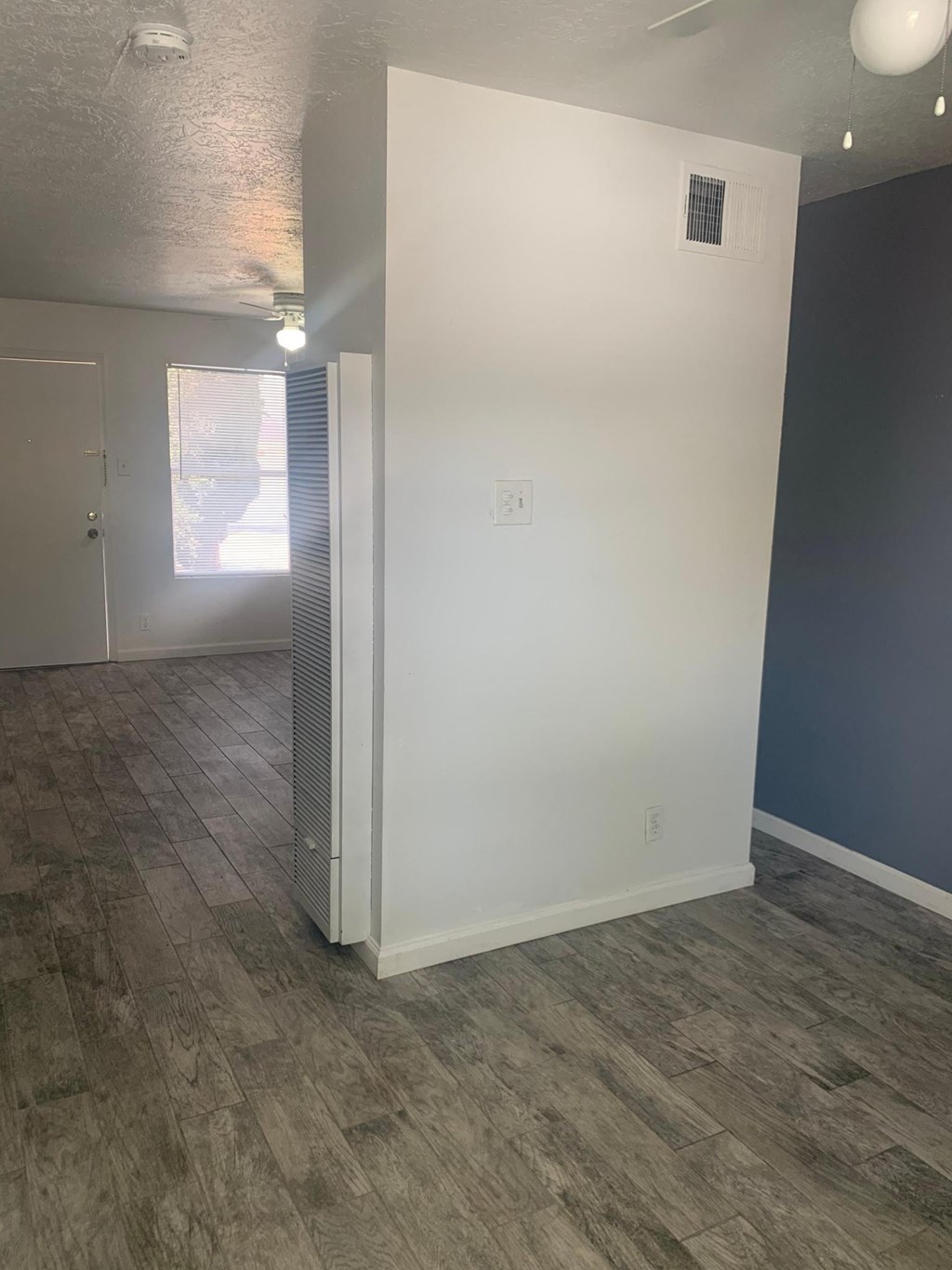 a living room with a white wall and wood floors