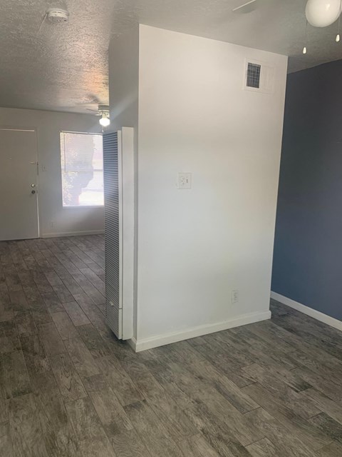 a living room with a white wall and wood floors