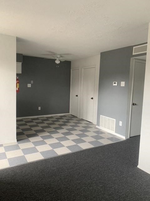 A room with a checkered floor and a ceiling fan.