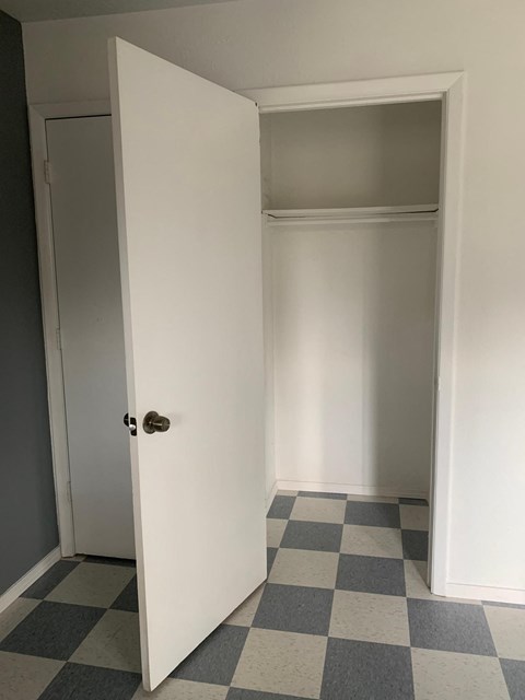 A white door is open to a room with a checkered floor.