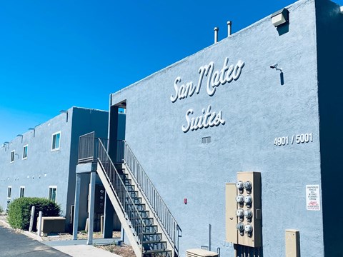 The San Mateo Suites building has a blue exterior and a staircase leading to the entrance.
