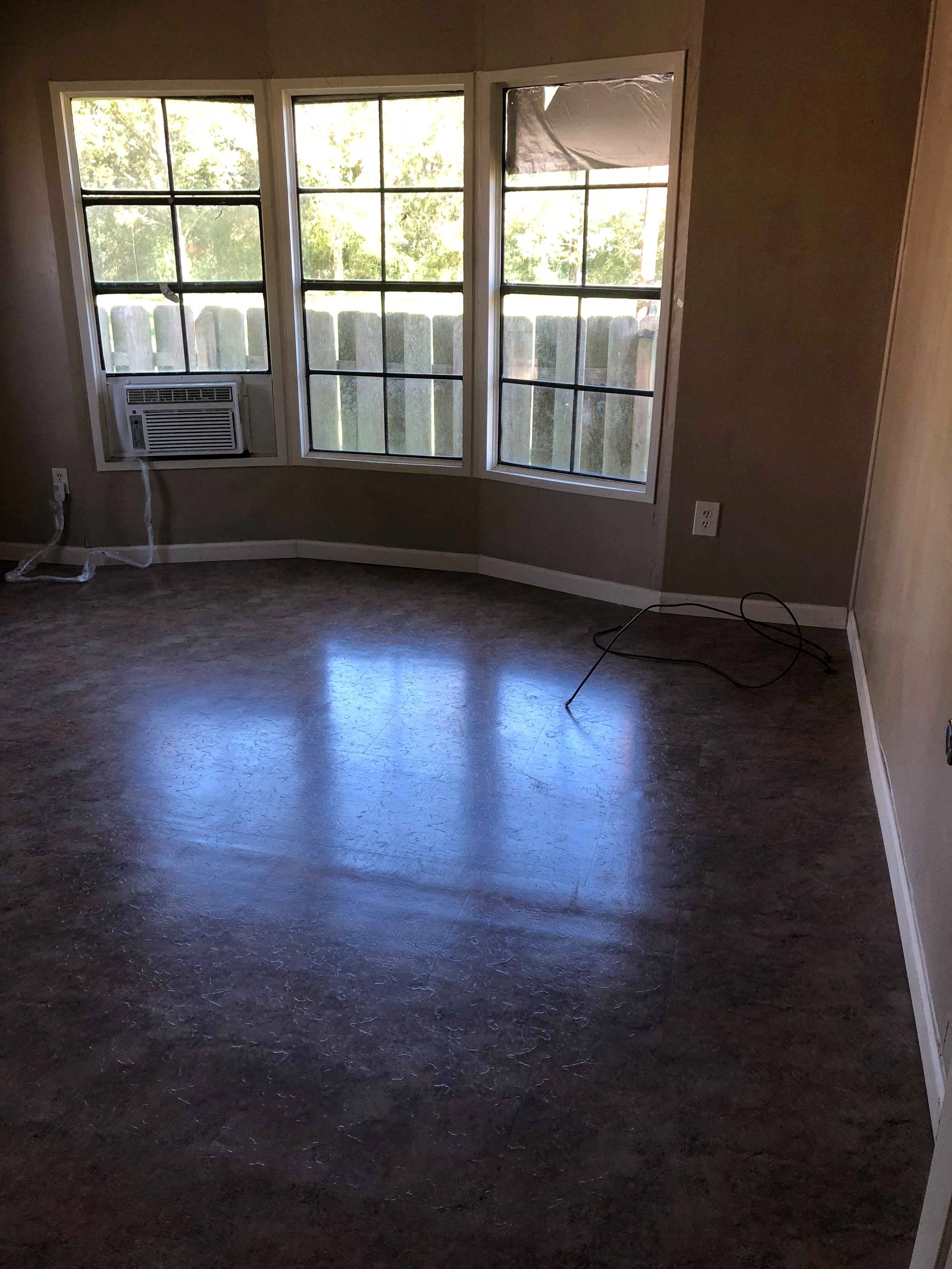 A room with a large window and a fan on the wall.