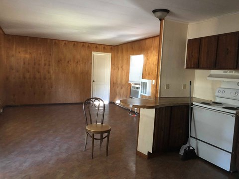 A kitchen with a chair and a refrigerator.