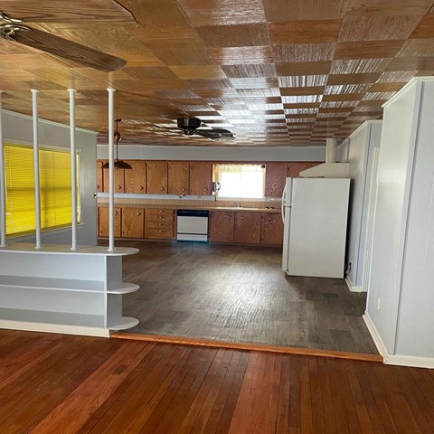 an empty kitchen with wood floors and a refrigerator