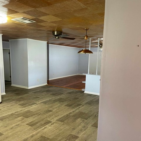 an empty living room with a wood floor and a ceiling fan