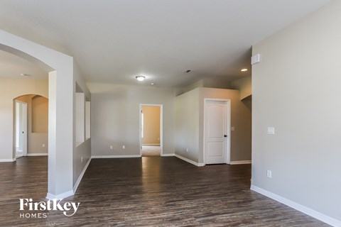 A spacious room with wooden floors and white walls, with a door on the right side.