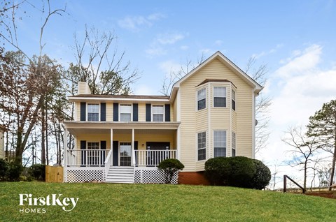 A two story house with a porch and a white picket fence.