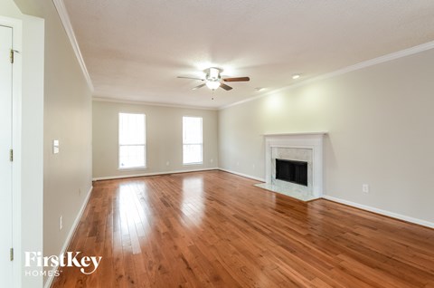 A spacious room with a fireplace and wooden floors.