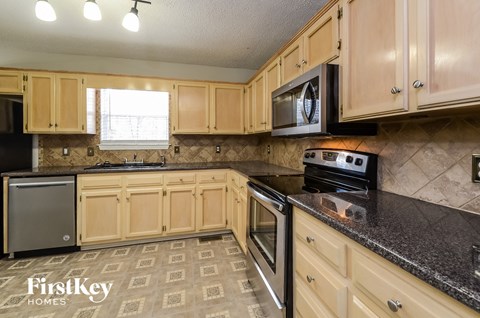 A kitchen with wooden cabinets and a black countertop.