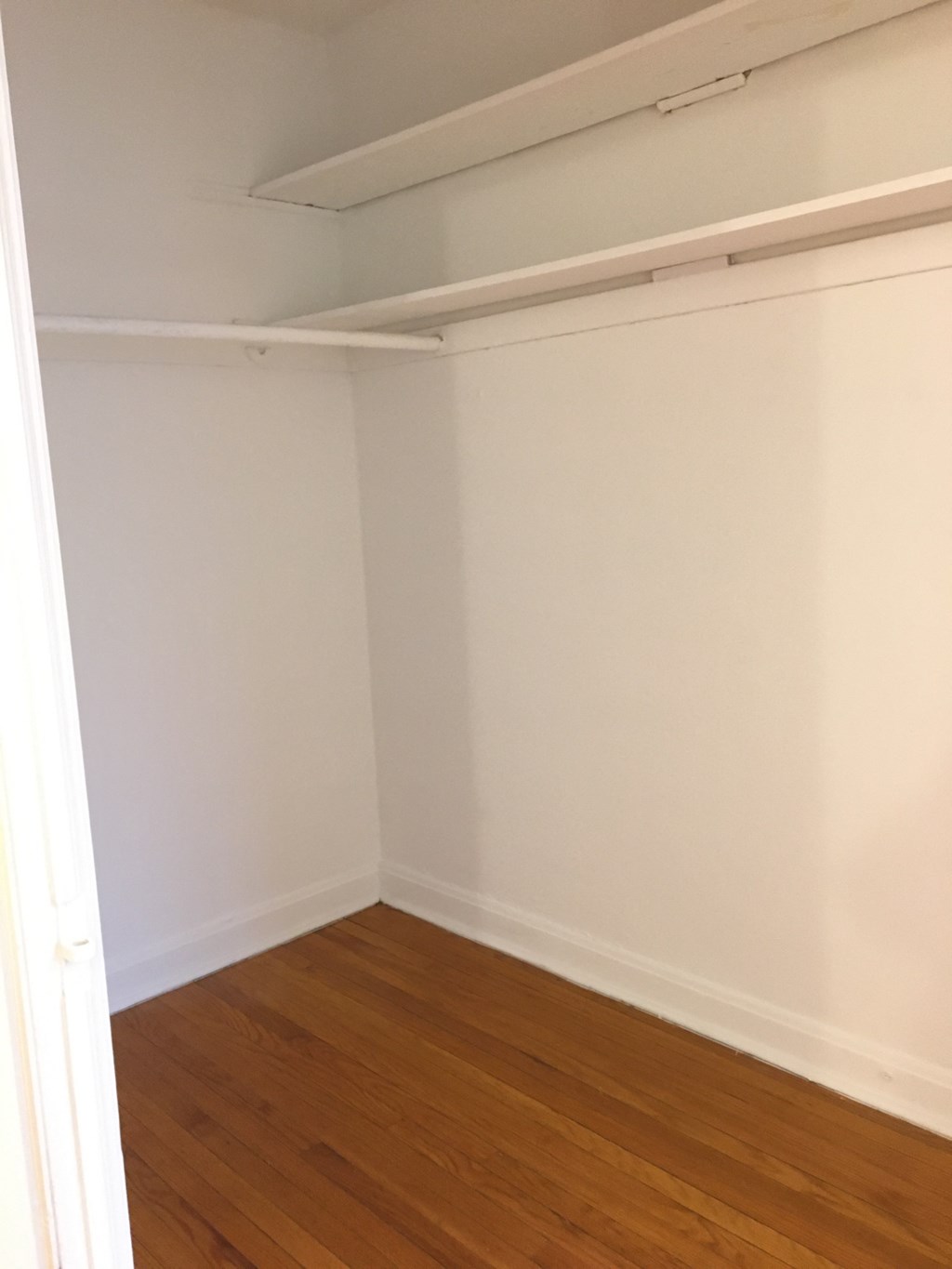the corner of a room with a wood floor and white walls