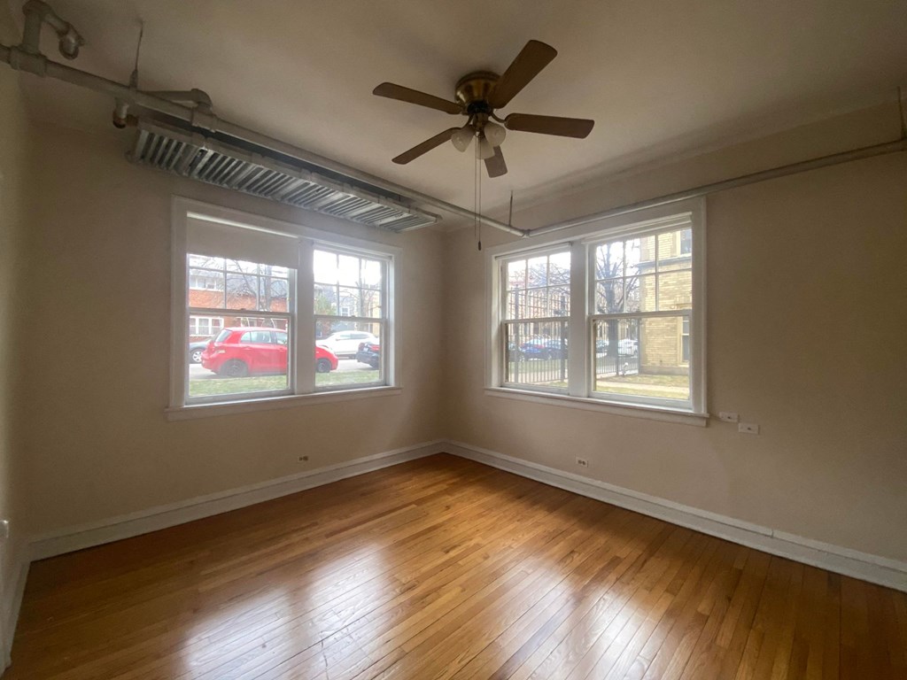 the living room of an empty house with a ceiling fan and three windows