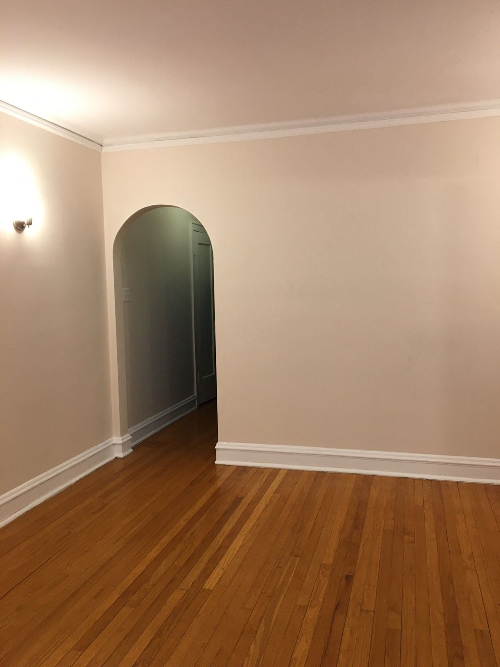 an arched doorway in a living room with wood floors and white walls