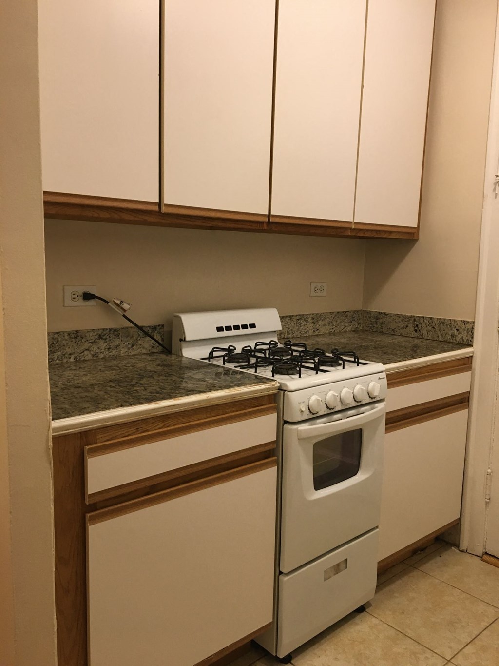 a kitchen with a stove and counters and white cabinets