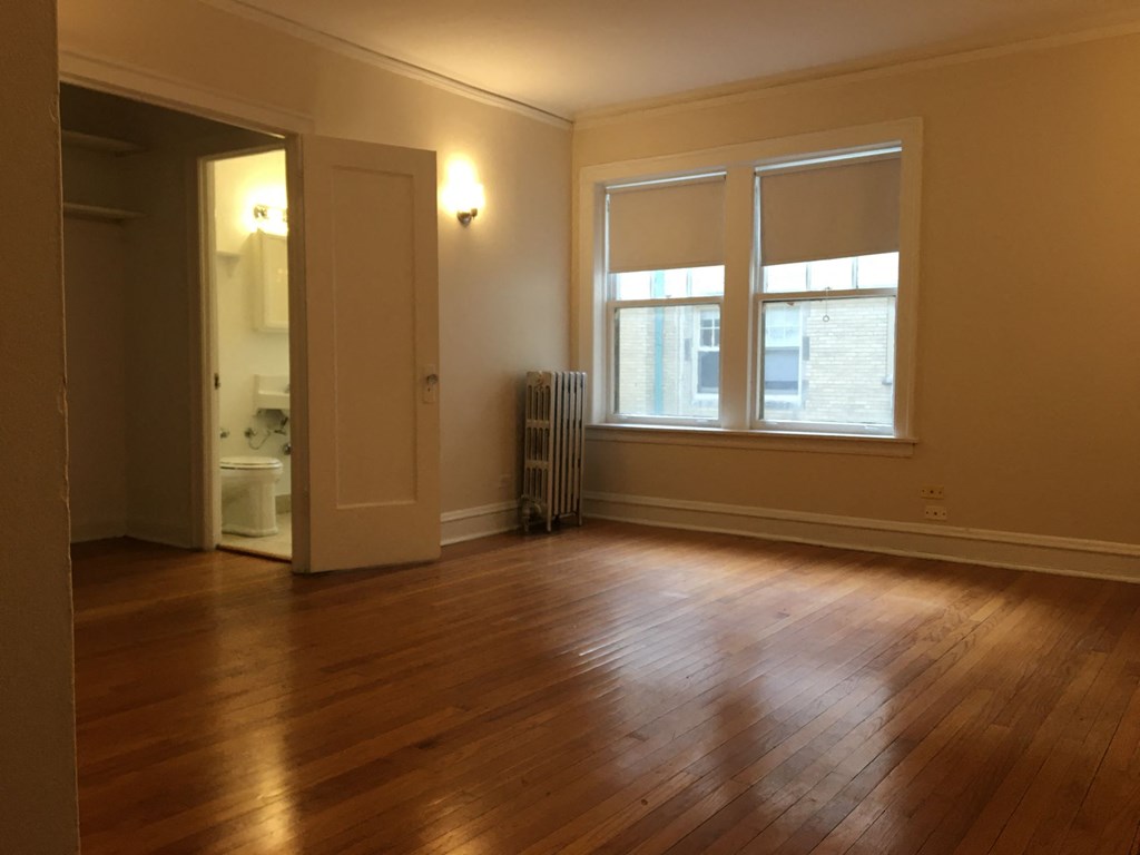 an empty living room with wood floors and a window
