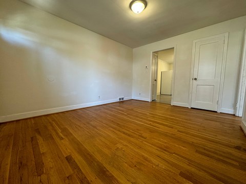 A room with wooden flooring and white walls.