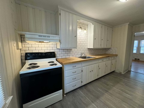 A kitchen with a black stove top oven and white cabinets.
