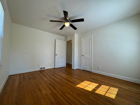 A room with a ceiling fan and wooden floors.