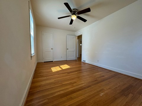 A room with a ceiling fan and wooden floors.