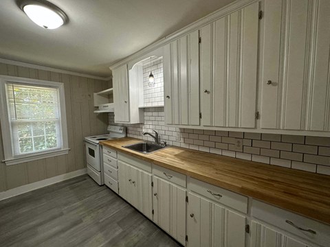 a kitchen with a wooden counter top and white cabinets