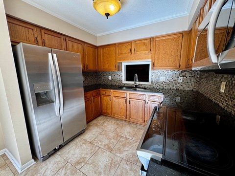 A kitchen with a black stove top oven and a silver refrigerator.