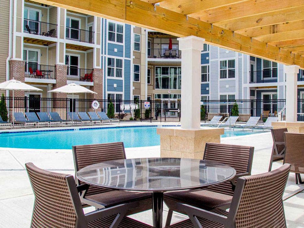 a patio with a table and chairs next to a swimming pool