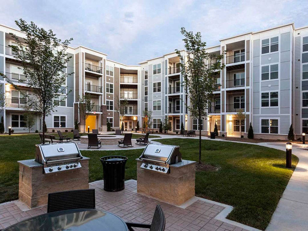 an exterior view of an apartment building with barbecue pits