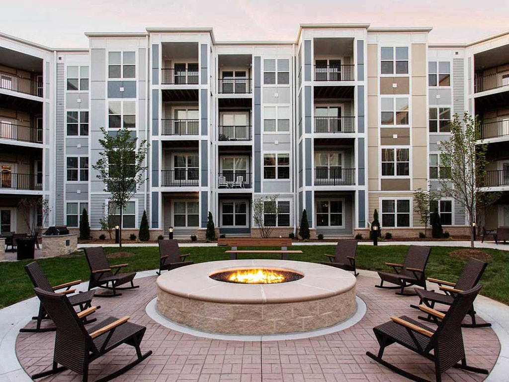 an outdoor area with a fire pit in front of an apartment building