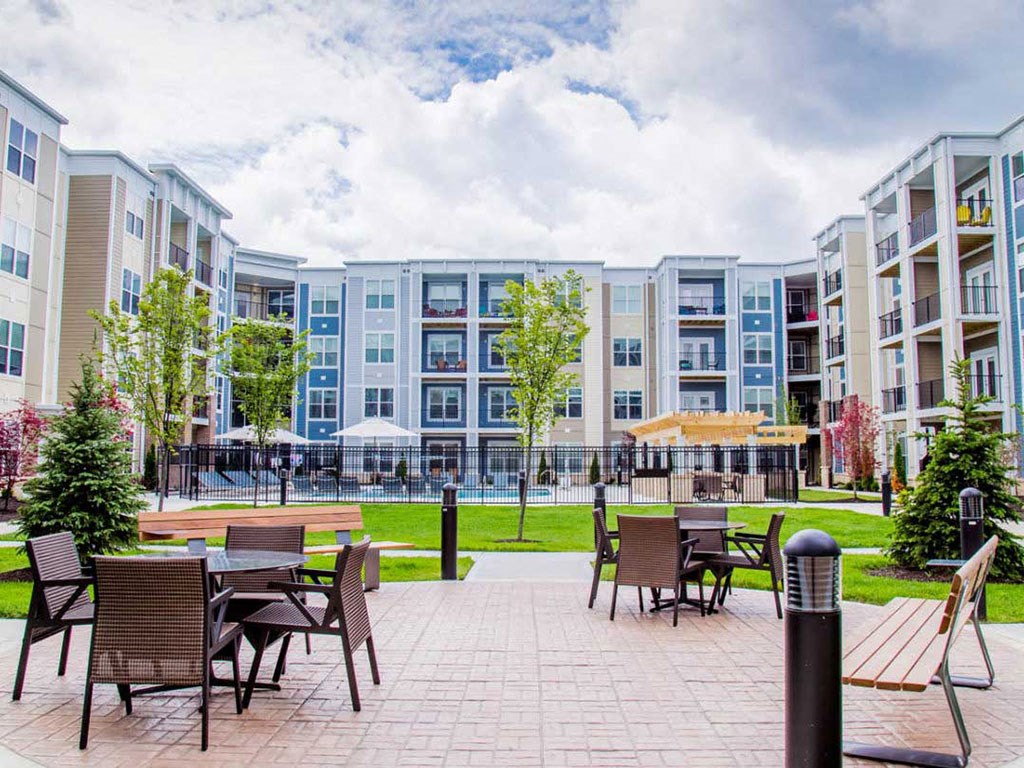 an outdoor patio with tables and chairs in front of an apartment building