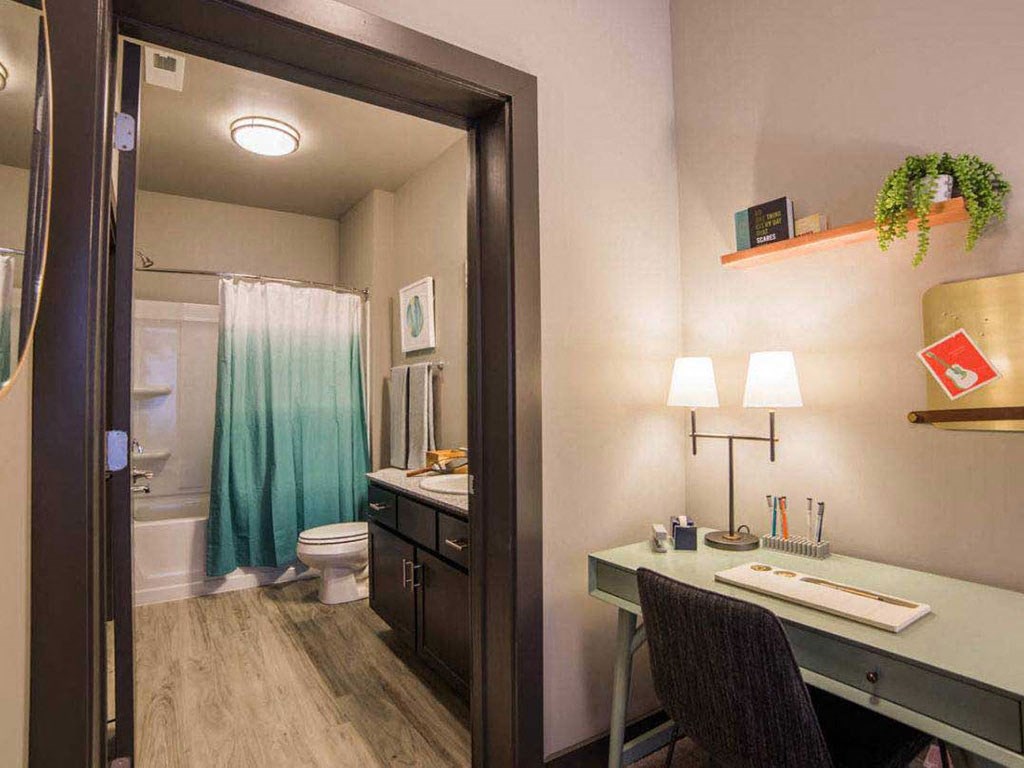 a small office with a desk in a room with a bathroom