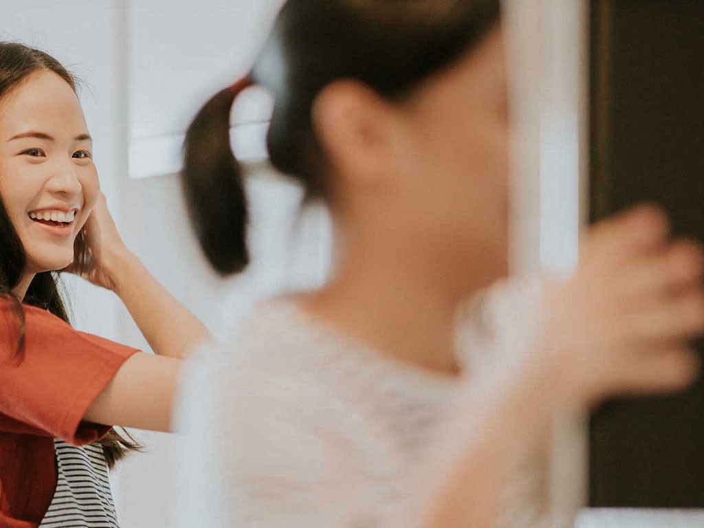 a woman brushing her hair in front of a mirror