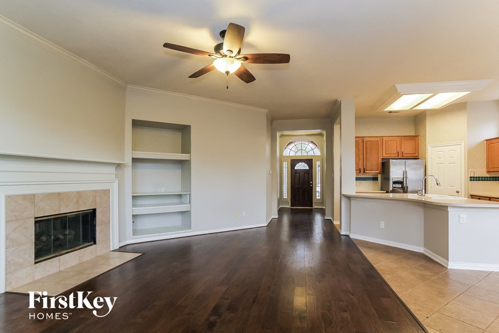 A spacious living room with a fireplace and a ceiling fan.