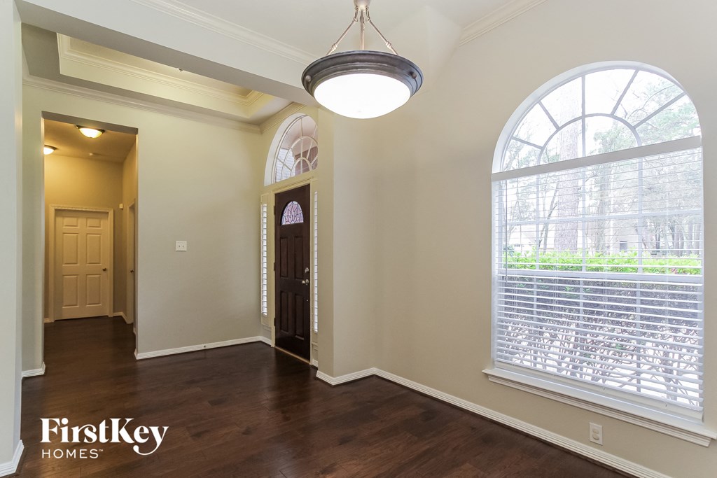 A room with a large arched window and a wooden floor.