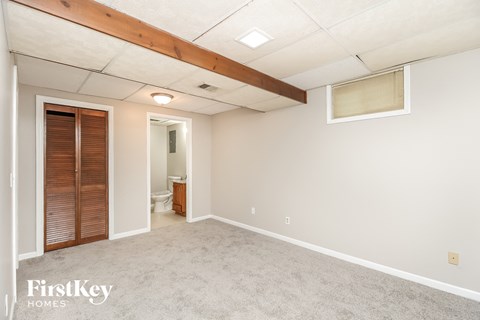 a spacious living room with carpet and a door to the bathroom