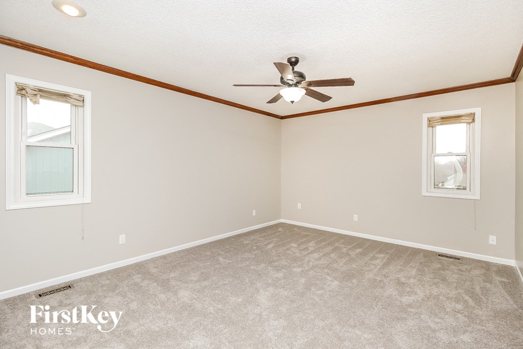 the master bedroom has a carpeted floor and a ceiling fan