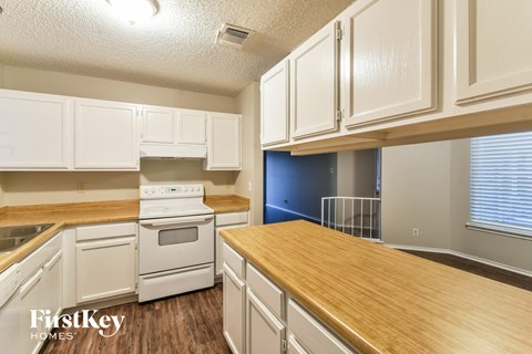 A kitchen with white cabinets and a wooden counter top.