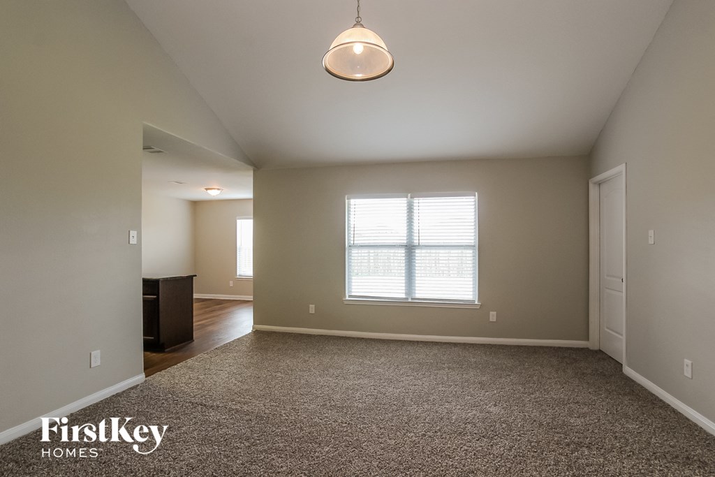 an empty living room with carpet and a window