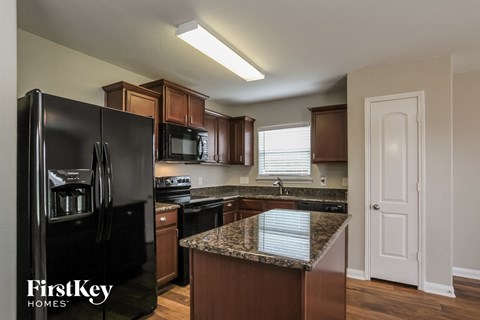 an updated kitchen with black appliances and granite counter tops