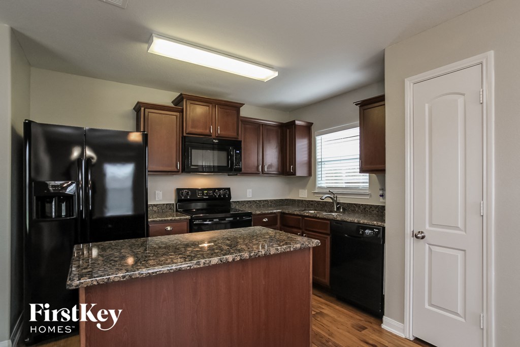 full interior view of a kitchen with black appliances and granite counter tops