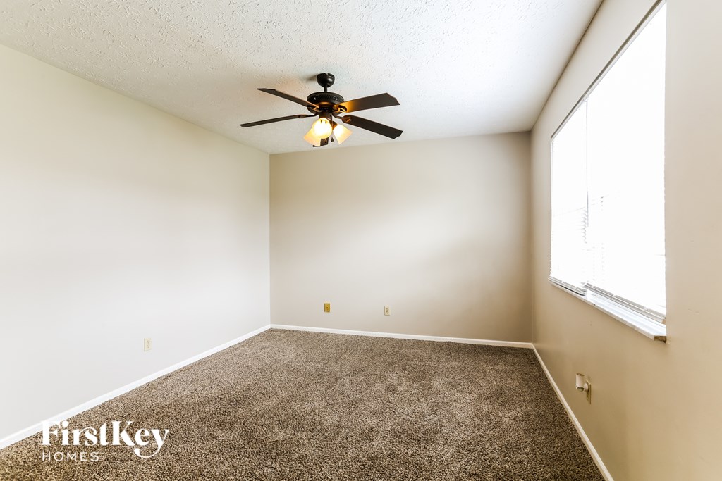 A room with a carpet floor and a ceiling fan.