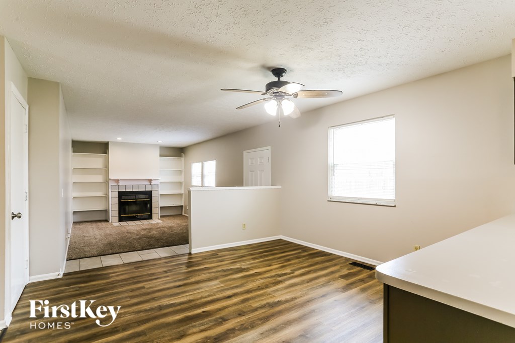 A spacious room with a wood floor and a ceiling fan.