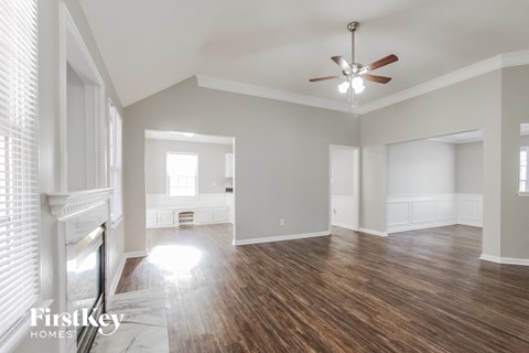 the living room and dining room with wood flooring and a ceiling fan