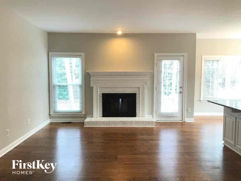 A spacious living room with a fireplace and wood flooring.