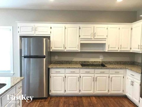 A kitchen with white cabinets and a stainless steel refrigerator.