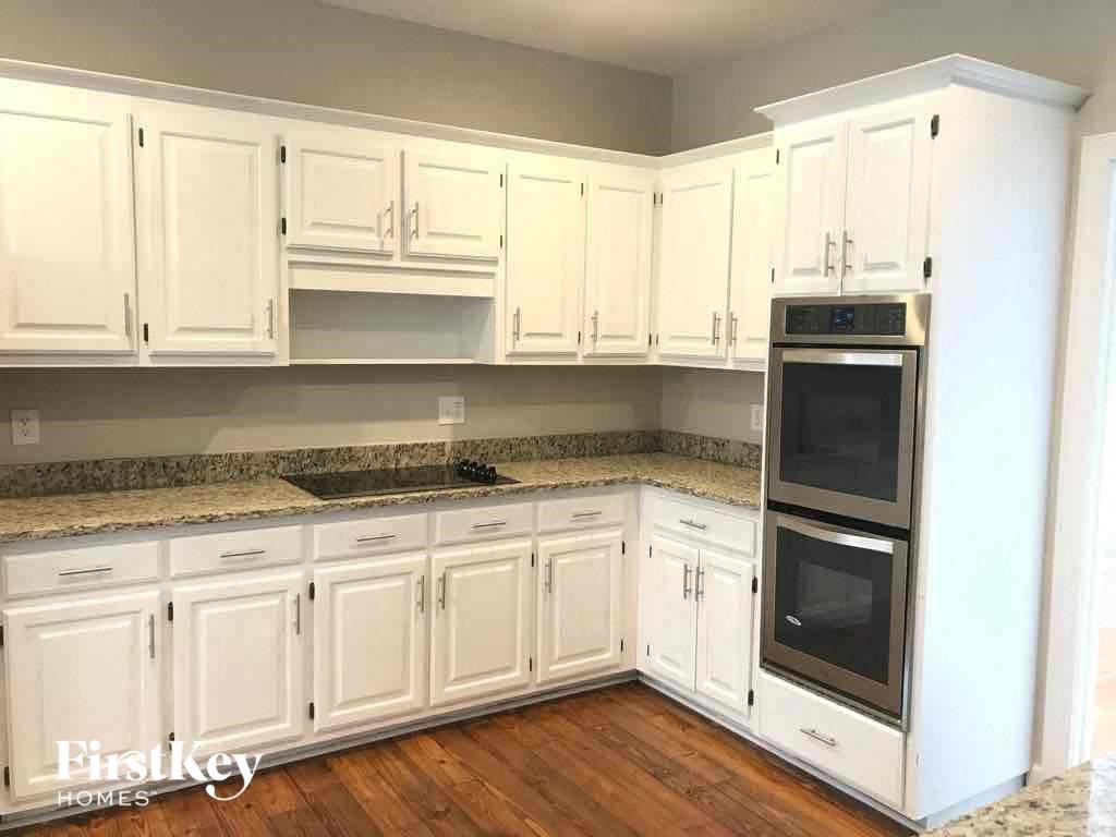 A kitchen with white cabinets and a granite countertop.