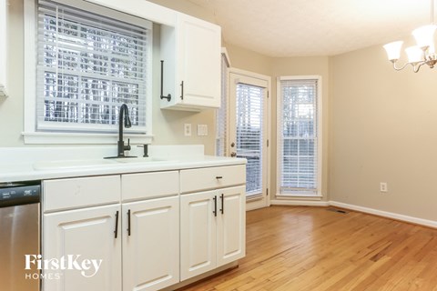 A kitchen with white cabinets and a black dishwasher.