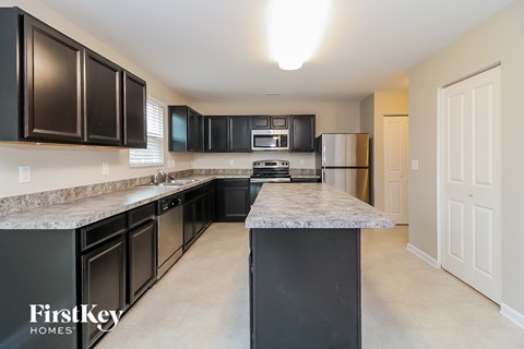 A kitchen with black cabinets and a marble countertop.