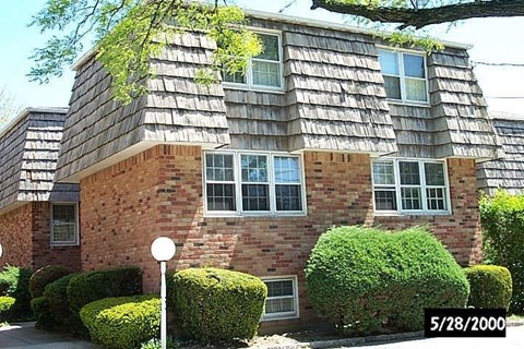 A house with a grey roof and a red brick wall.