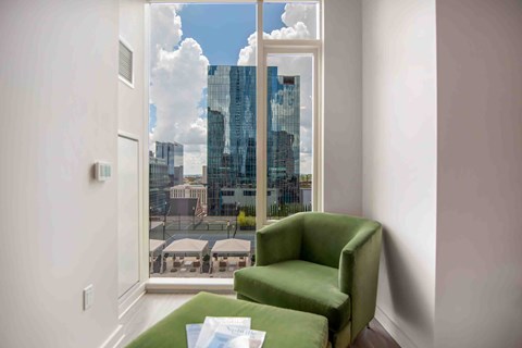 a living room with a green chair and a view of the city