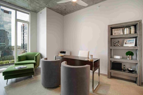 a living room with a desk and chairs and a window